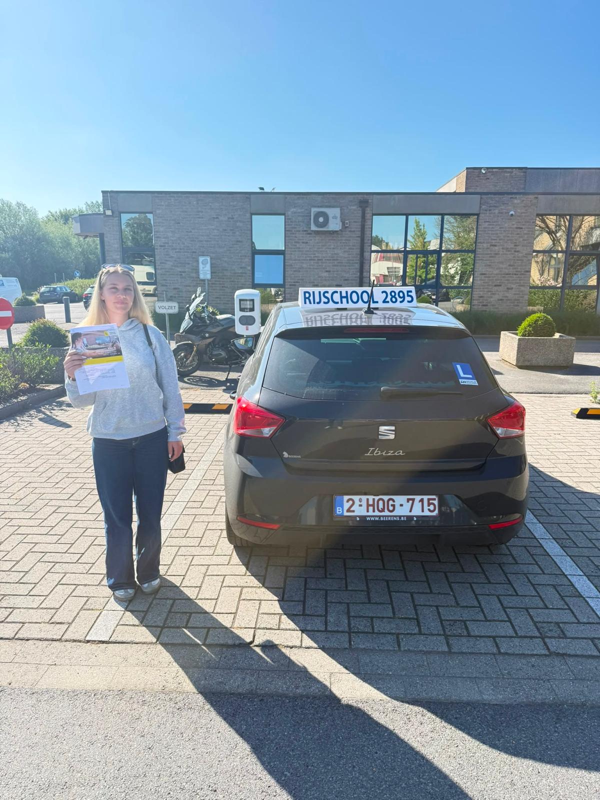 Leerling met haar resultaat naast de Seat Ibiza in de zon